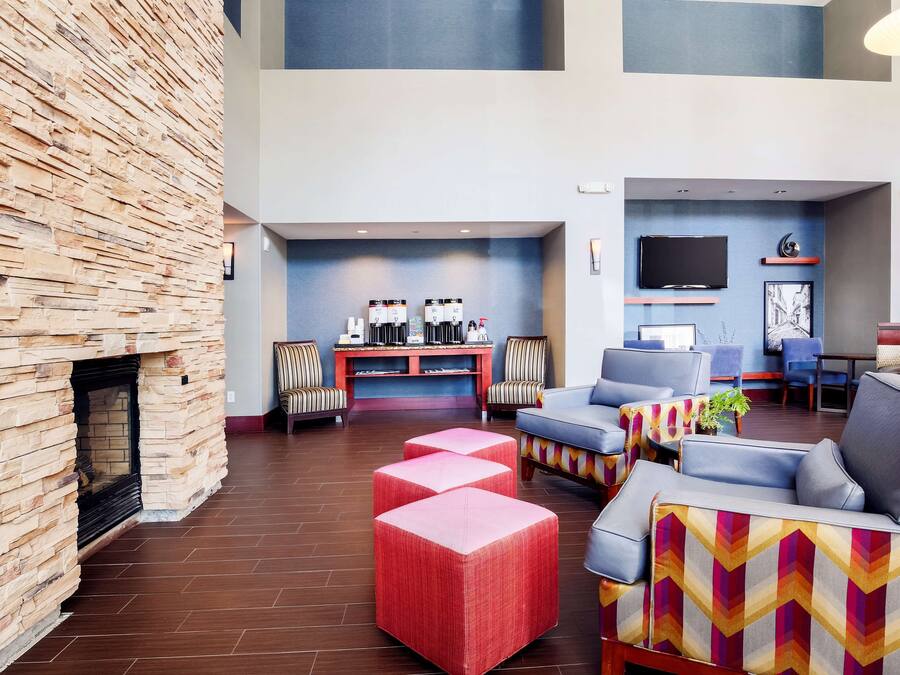 A spacious lobby with a stone fireplace, comfortable seating, a flat-screen TV, and a coffee station.