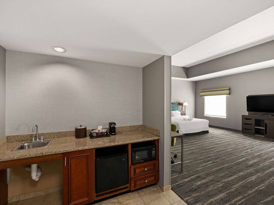 Une chambre d’hôtel équipée d’une kitchenette, d’un lit, d’une télévision et d’une fenêtre.