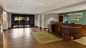 A reception area with a wooden floor, a reception desk, and a wall with a welcome sign.