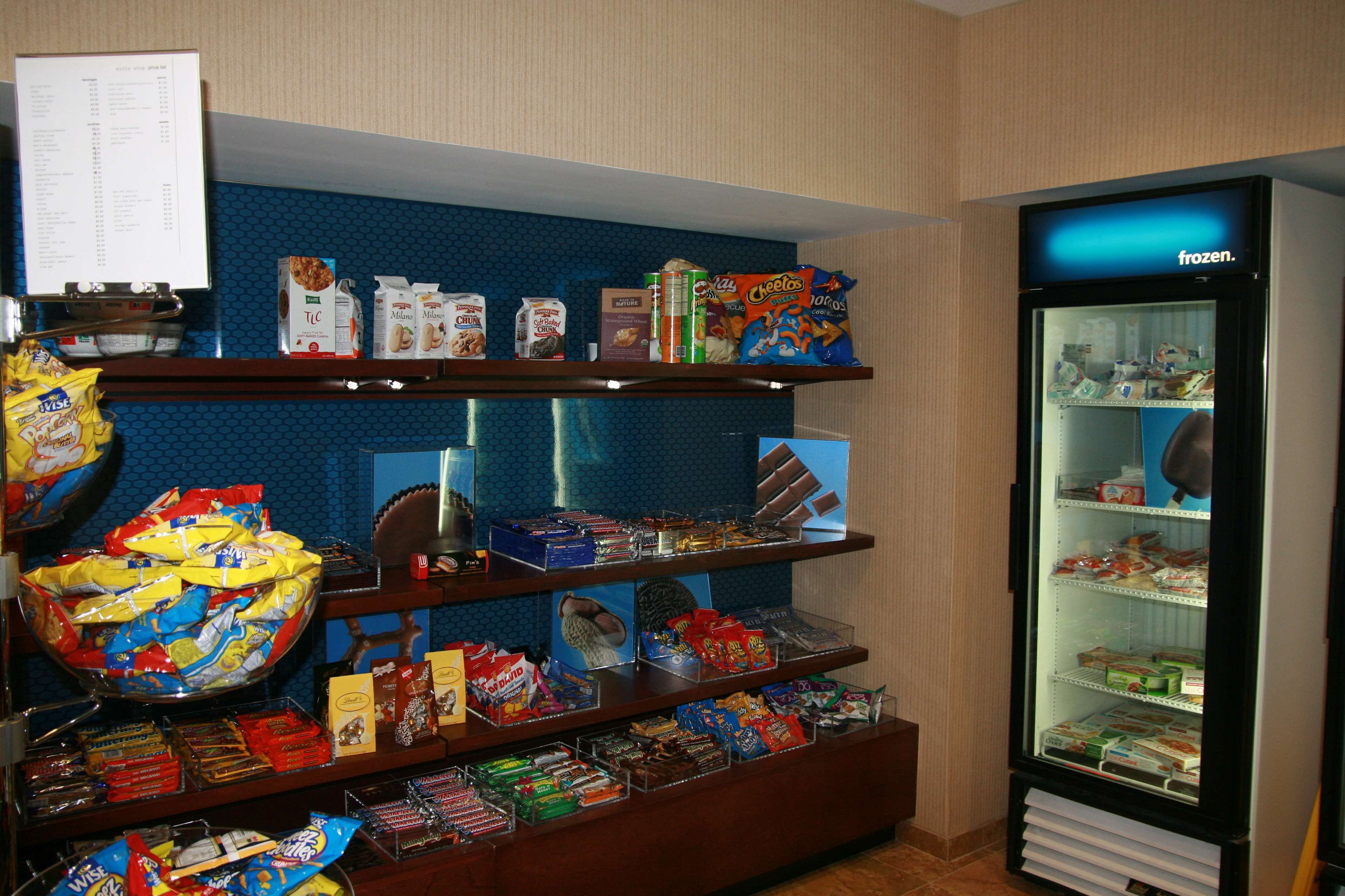 A snack display with various packaged foods and a frozen food refrigerator.