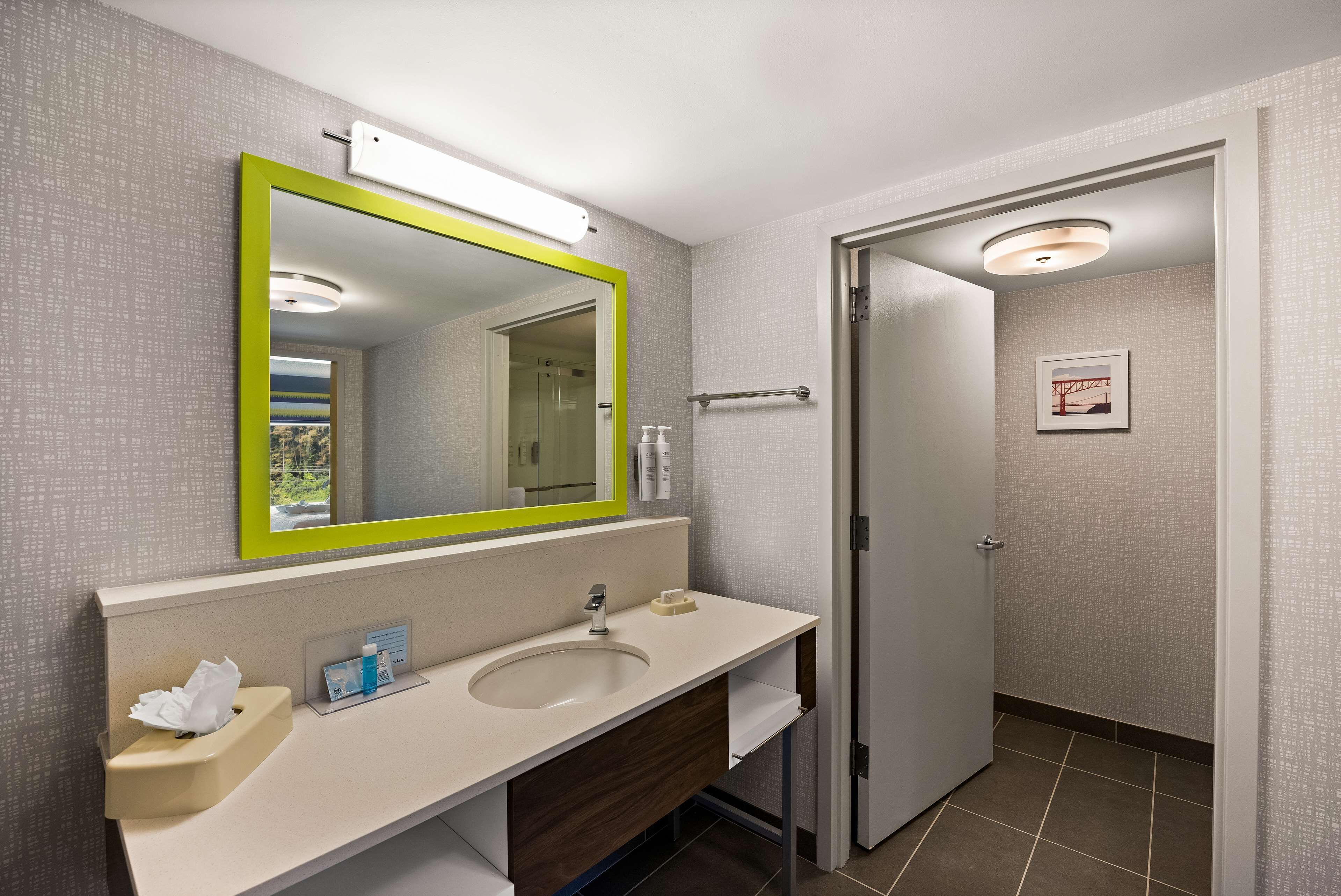 A modern bathroom with a large mirror, a sink, and a toilet.