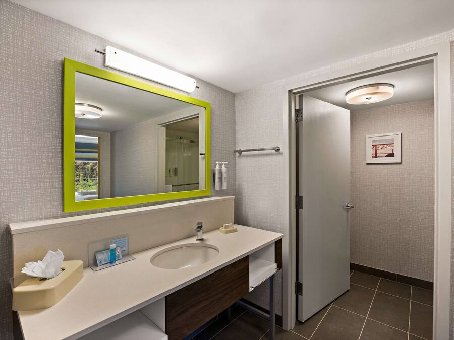 Un baño moderno con un espejo grande, un lavabo y un inodoro.