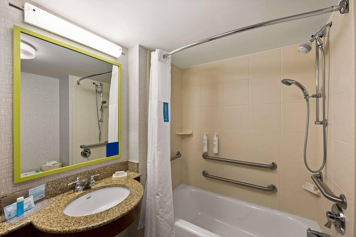 A bathroom with a sink, mirror, and bathtub.