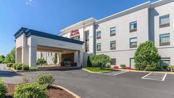 Un hotel moderno con entrada despejada, estacionamiento y jardines bien cuidados.