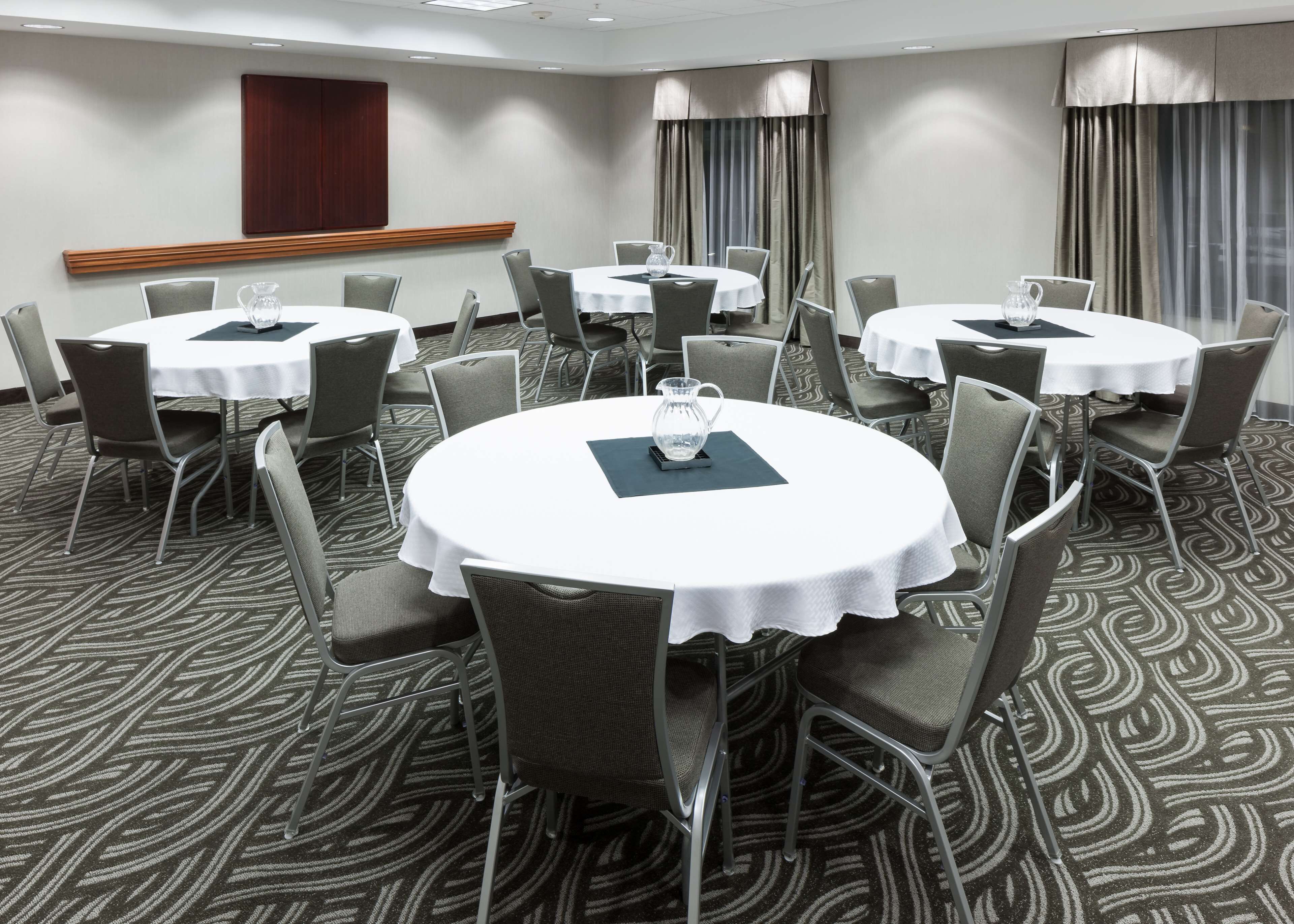 A conference room with round tables, grey chairs, and a patterned carpet.