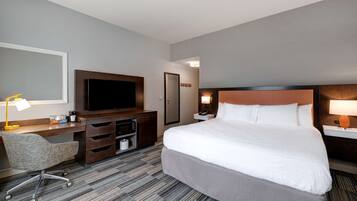 Habitación de hotel con una cama grande, un escritorio, un televisor de pantalla plana, una silla y una lámpara de escritorio.