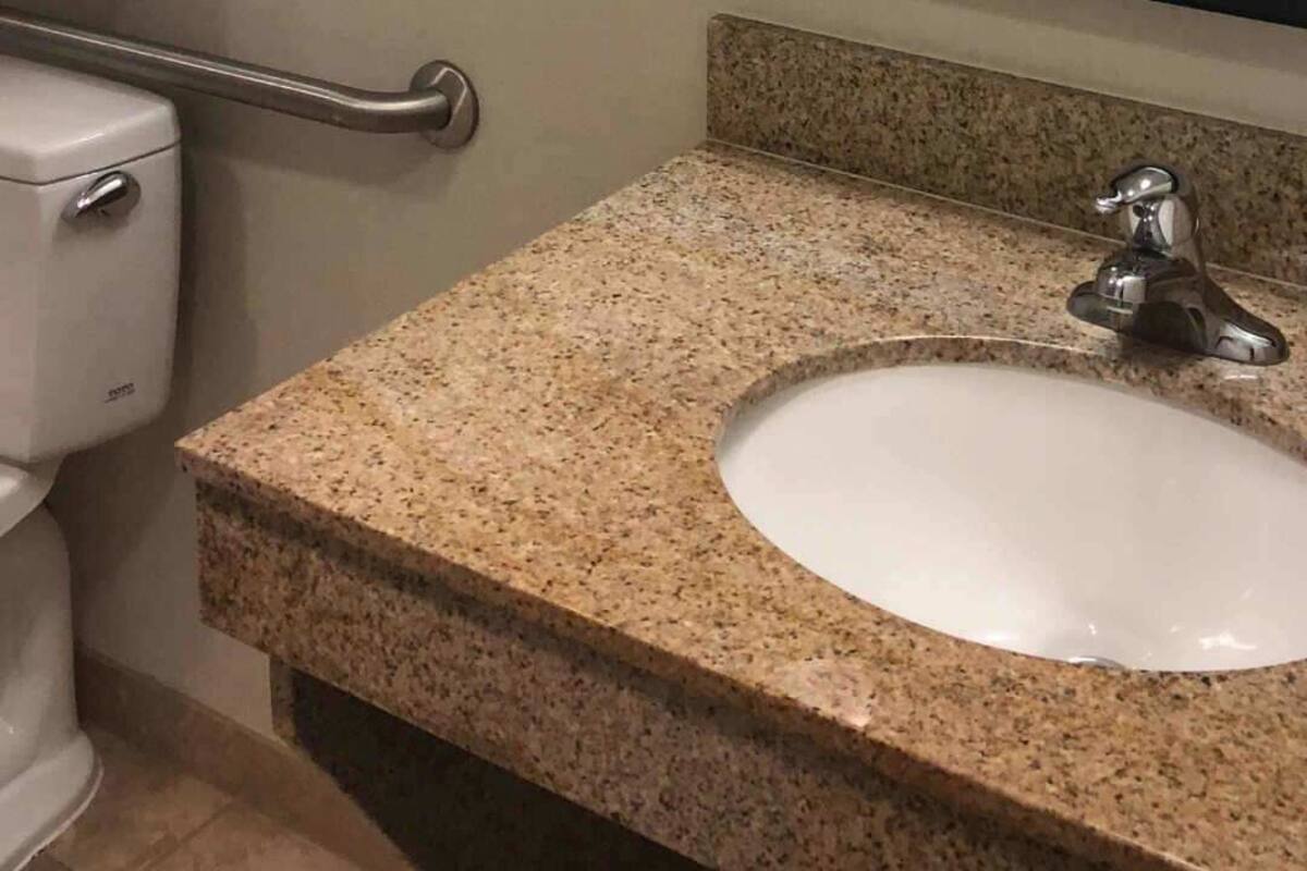 Une salle de bain équipée d’un lavabo, d’un miroir, d’un porte-serviettes et d’une douche.