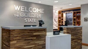 A reception desk with a "Welcome to the Golden State" sign, a "Sweets and Treats" display, and a "Hilton Honors" badge.