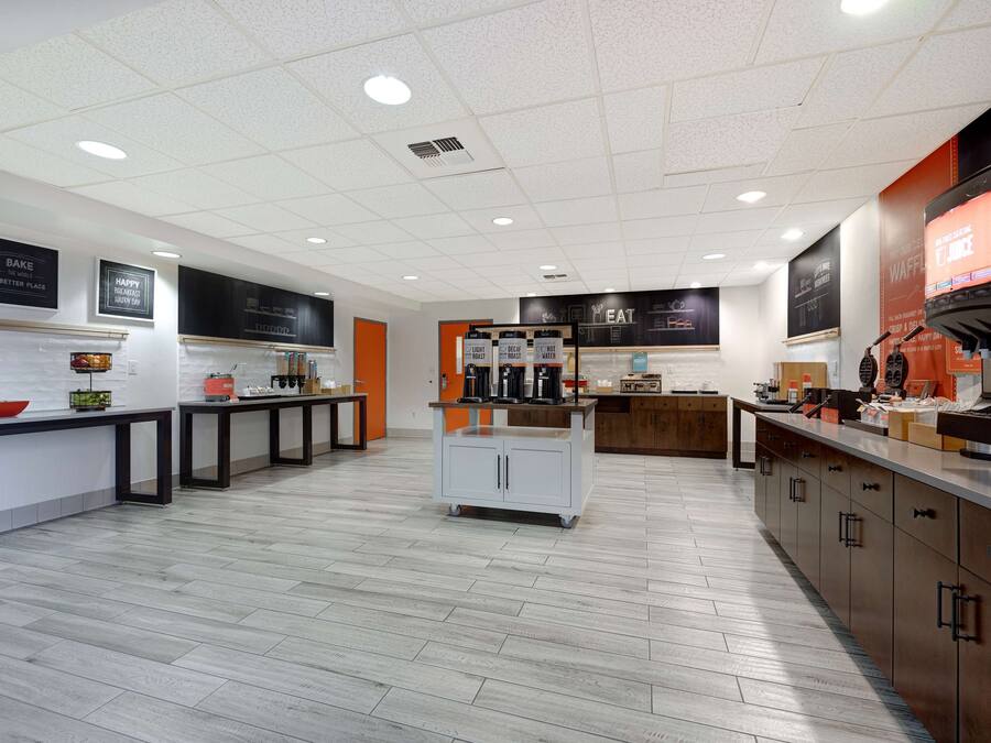Une cuisine moderne avec des meubles blancs, un îlot central et un coin café.