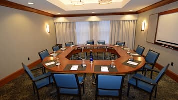 Une salle de conférence dotée d’une grande table ovale, de chaises bleues et d’un tableau blanc fixé au mur.