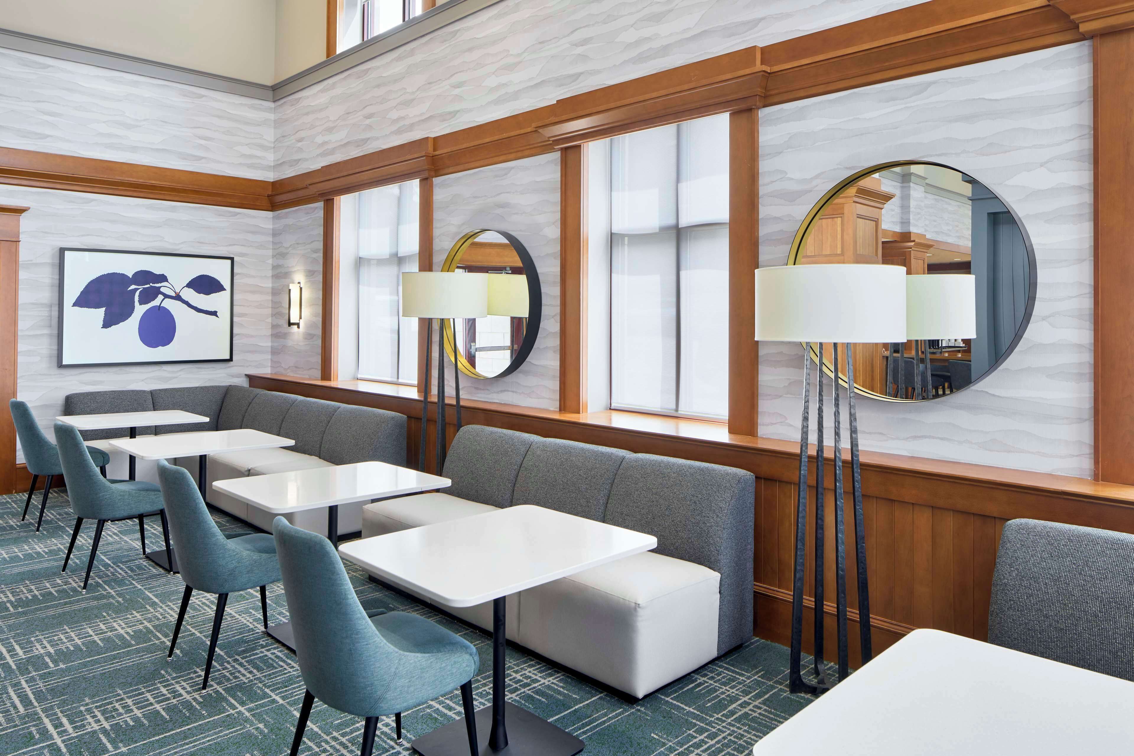 A hotel lobby with a seating area, tables, and a large mirror.
