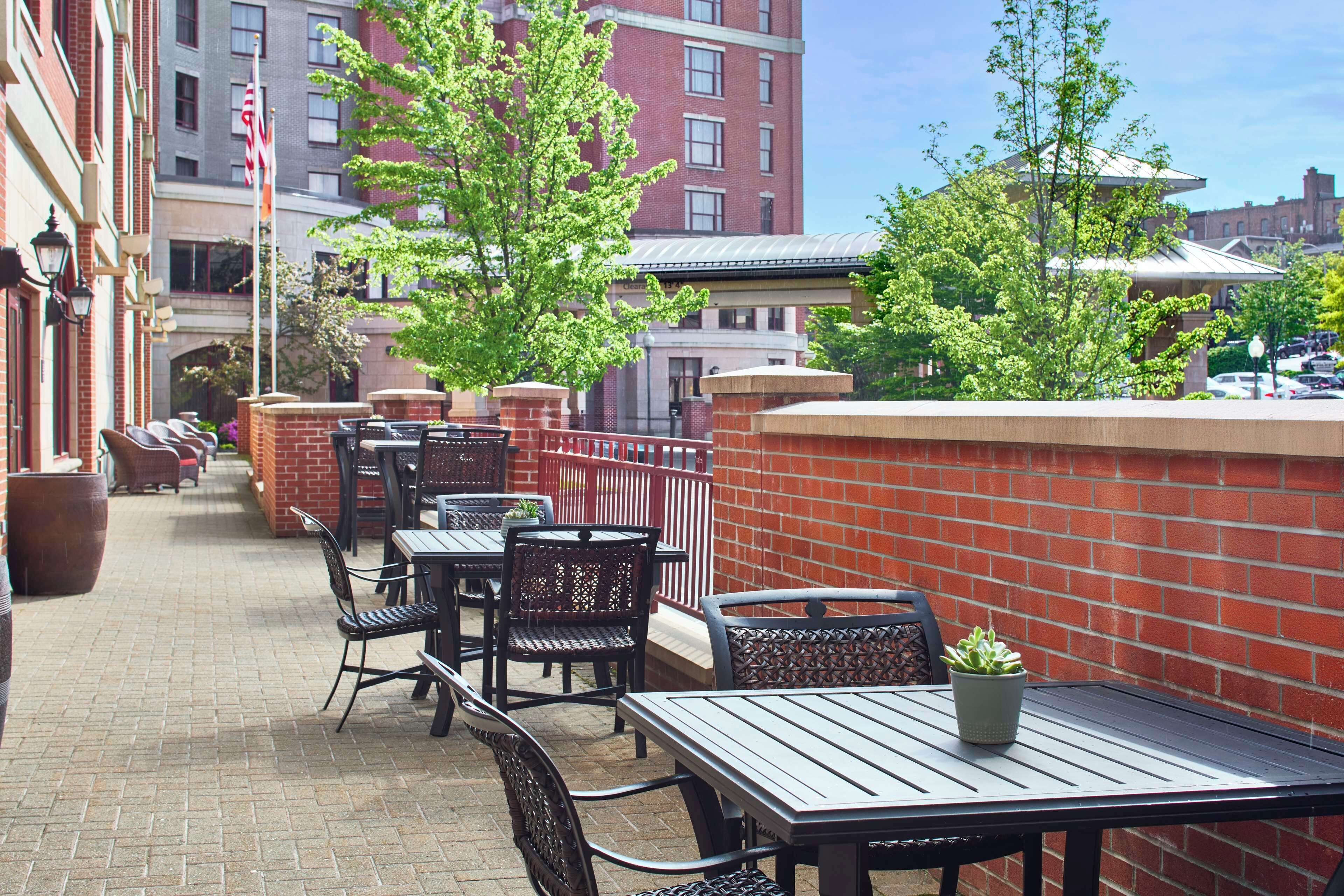 An outdoor patio with brick walls, metal tables, and chairs.