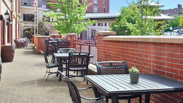 An outdoor patio with brick walls, metal tables, and chairs.