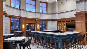 A spacious bar area with a large island, high ceilings, and large windows.