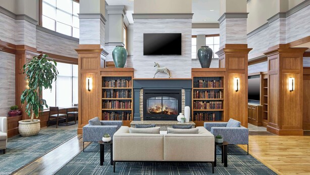 A spacious lobby with a fireplace, comfortable seating, and a large bookshelf.