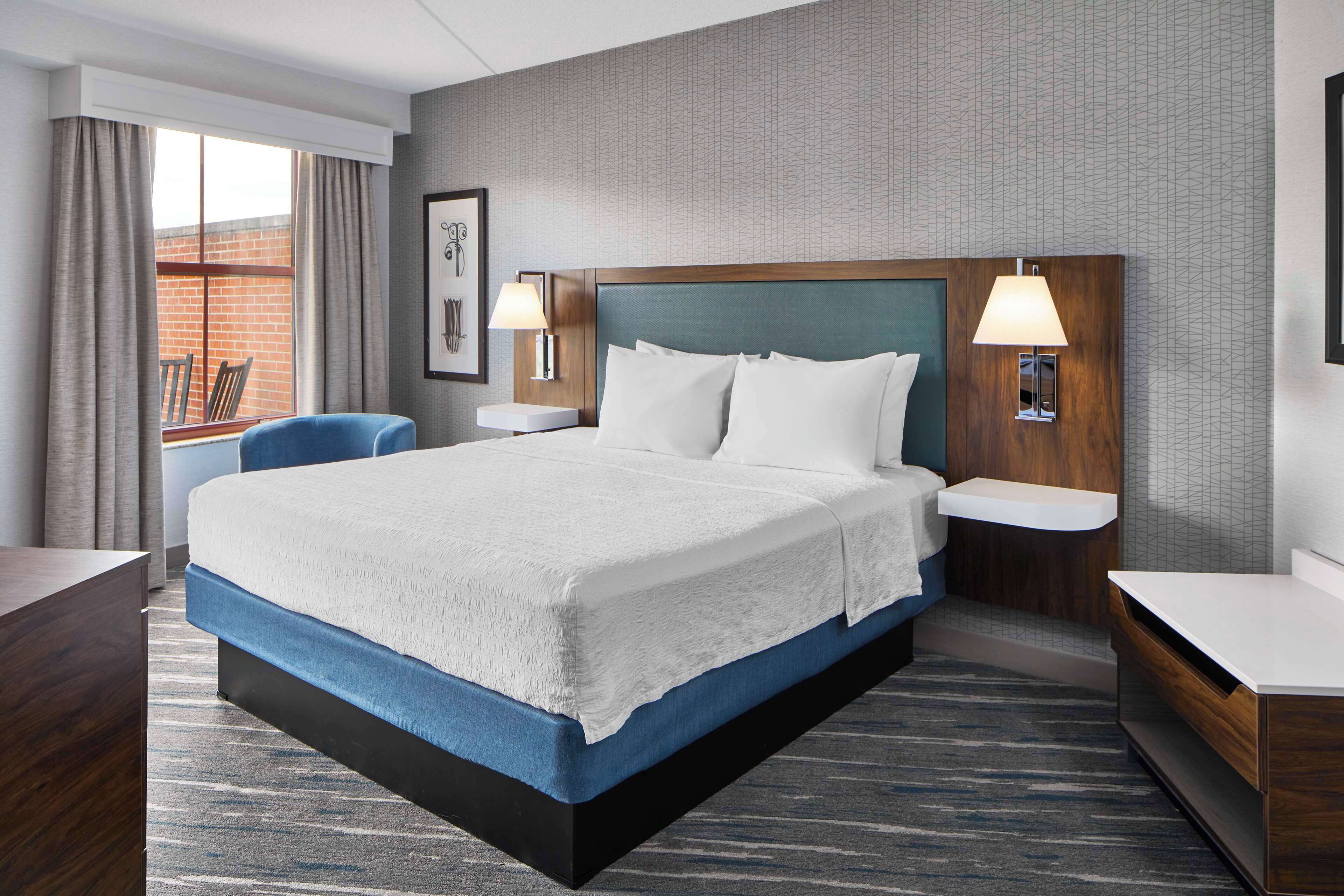 A hotel room with a large bed, two bedside tables, a desk, and a chair.