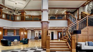 A spacious lobby with a checkered floor, a staircase, and a reception desk.
