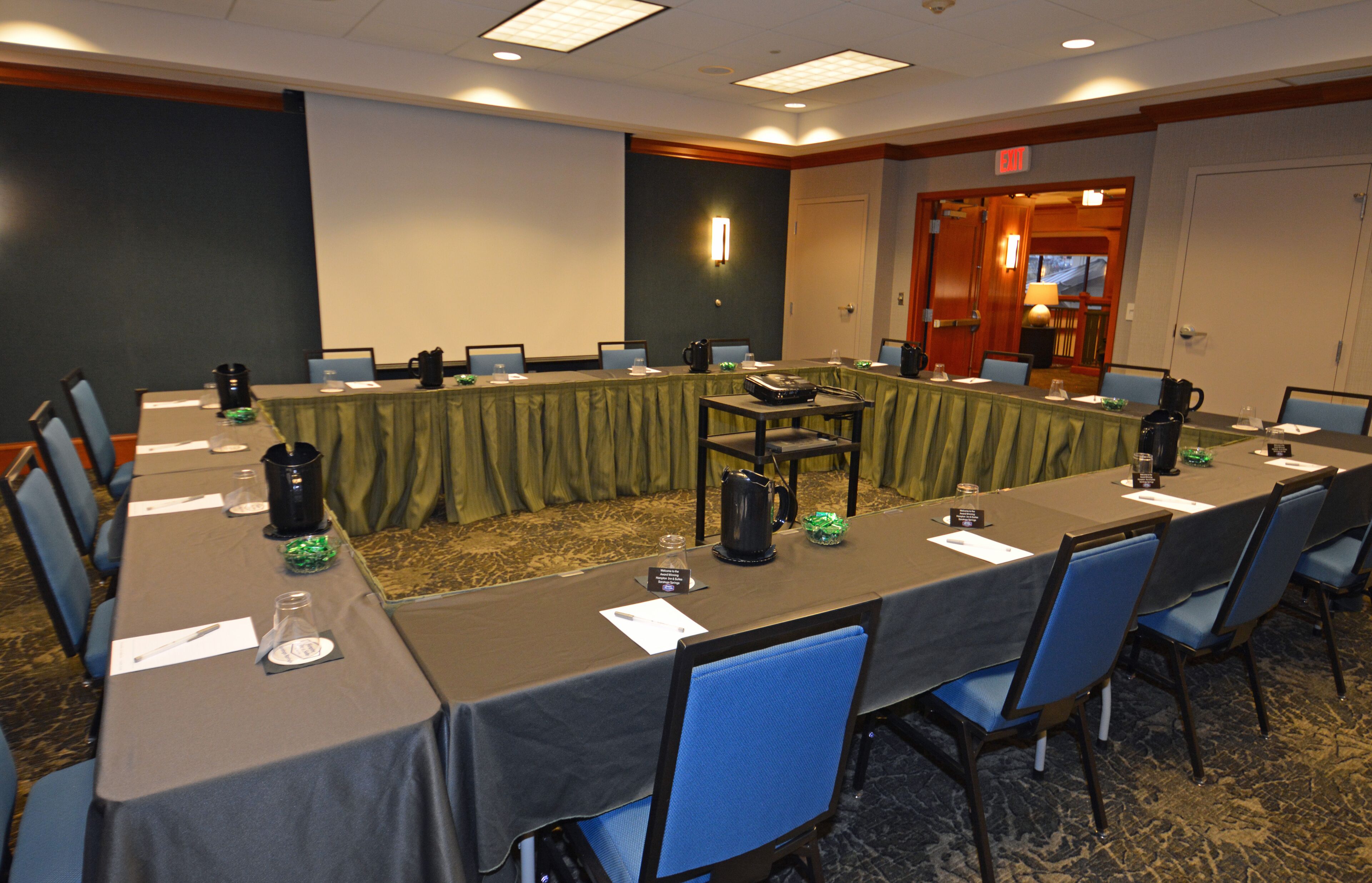 Une salle de conférence équipée d’une longue table, de chaises, de plaques nominatives et d’un coin café.