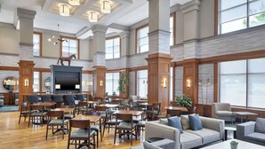 A spacious lobby with a fireplace, multiple seating areas, and large windows.
