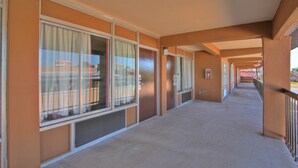 A corridor with large windows, a ventilation system, and a railing.