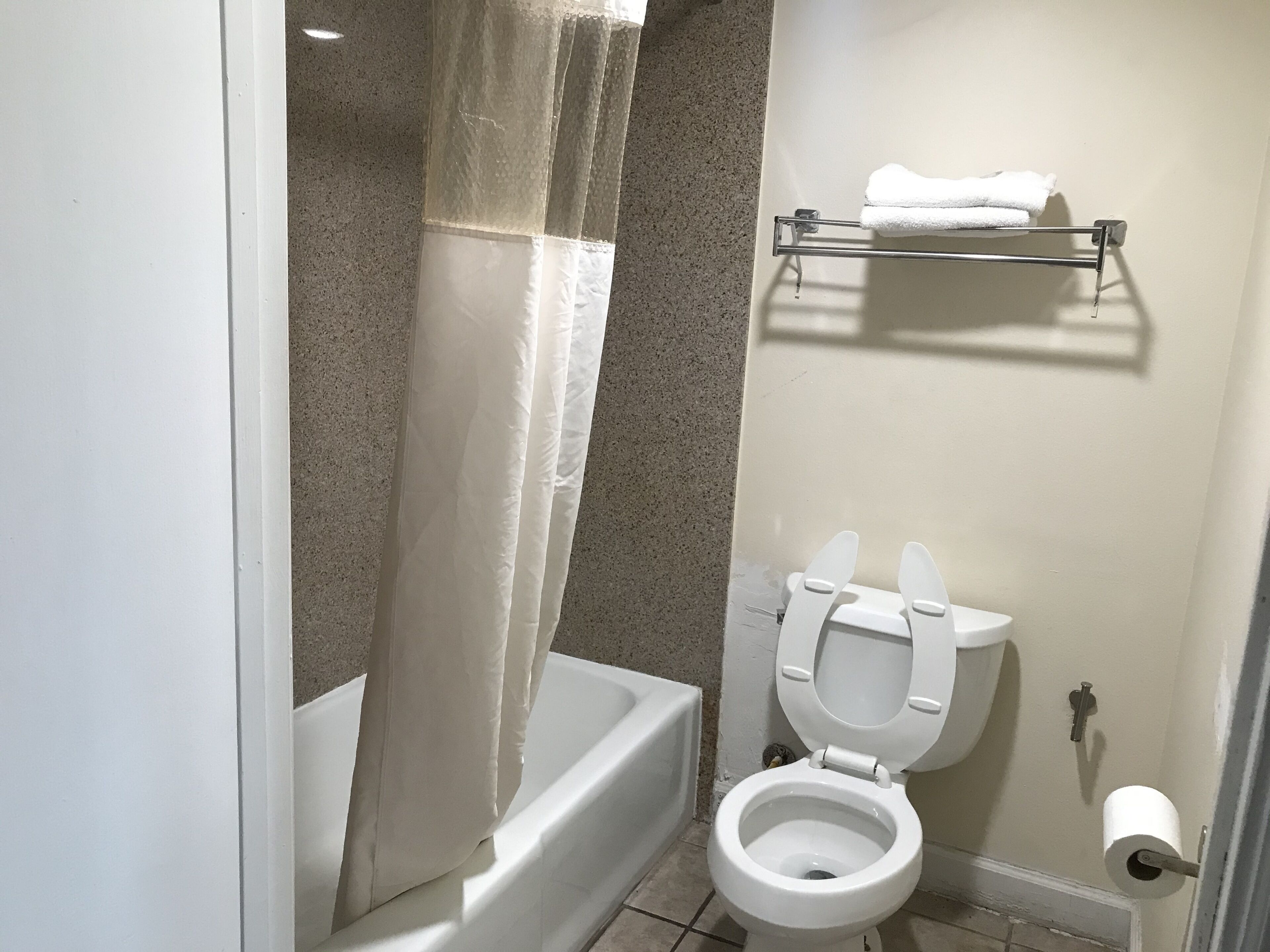 A bathroom with a bathtub, toilet, and a towel rack.