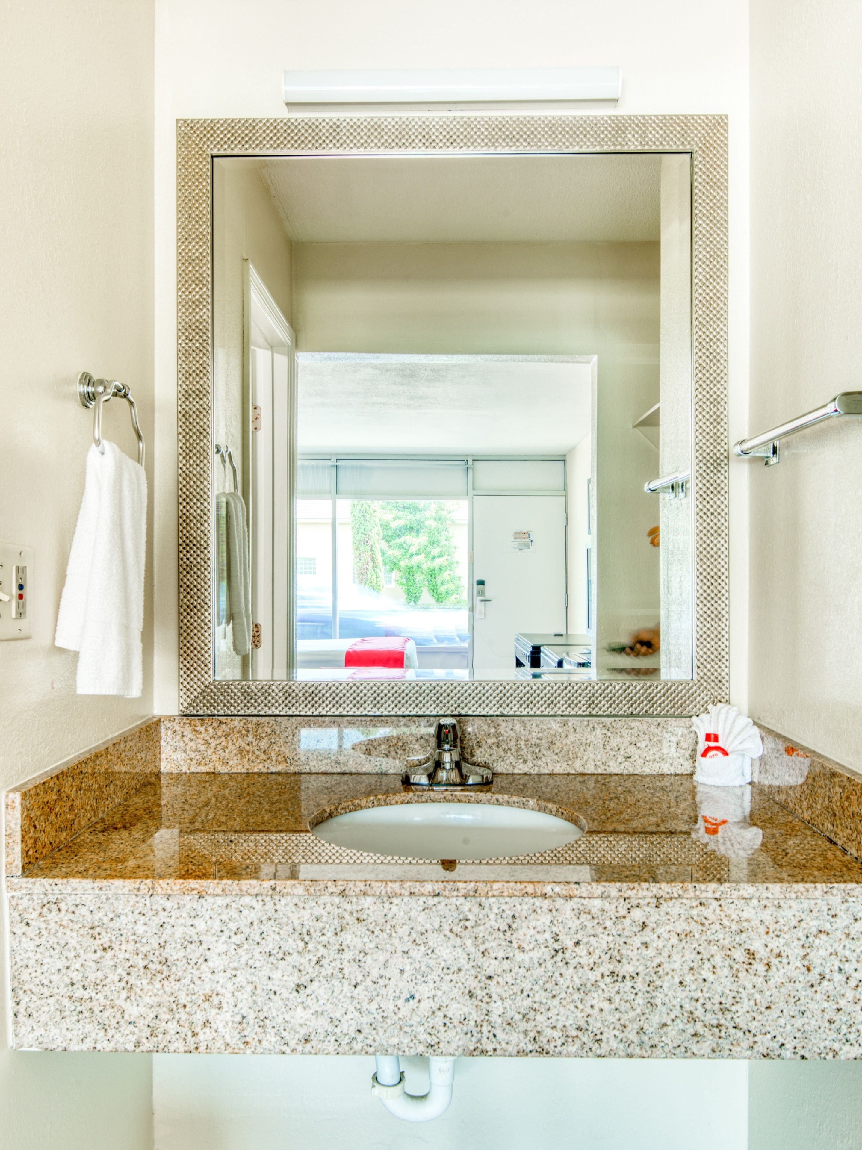 Ein Badezimmer mit einer Granit-Arbeitsplatte, einem Waschbecken, einem Spiegel und einem Handtuchhalter.