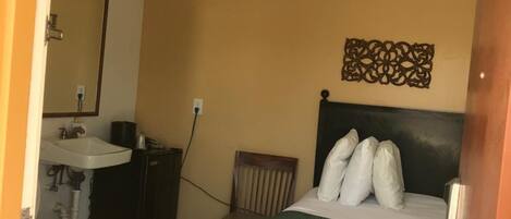 A hotel room with a bed, a chair, a sink, and a toilet.