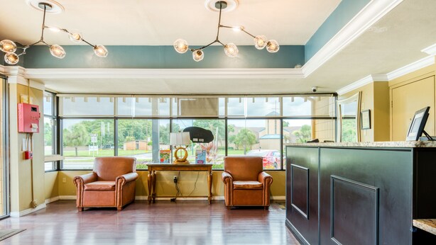 A spacious room with two leather chairs, a wooden table, and a large window offering a view of the outdoors.