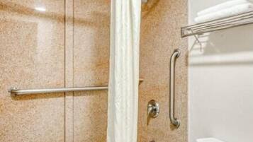A bathroom with a bathtub, toilet, and shower area.