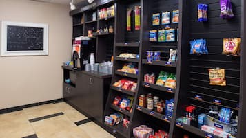 A kitchenette area with a coffee machine, a chalkboard menu, and shelves stocked with snacks and condiments.