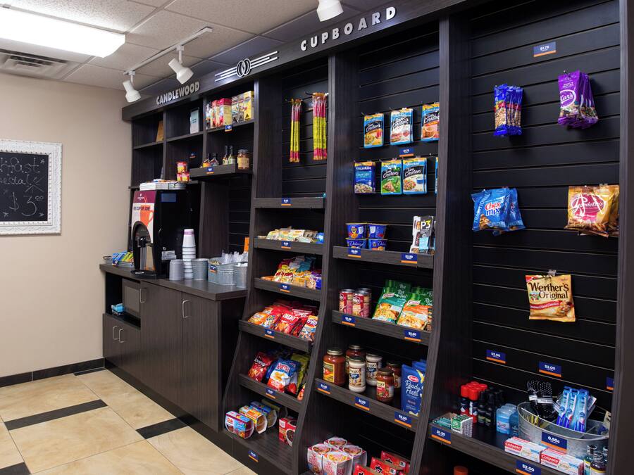 A kitchenette area with a coffee machine, a chalkboard menu, and shelves stocked with snacks and condiments.