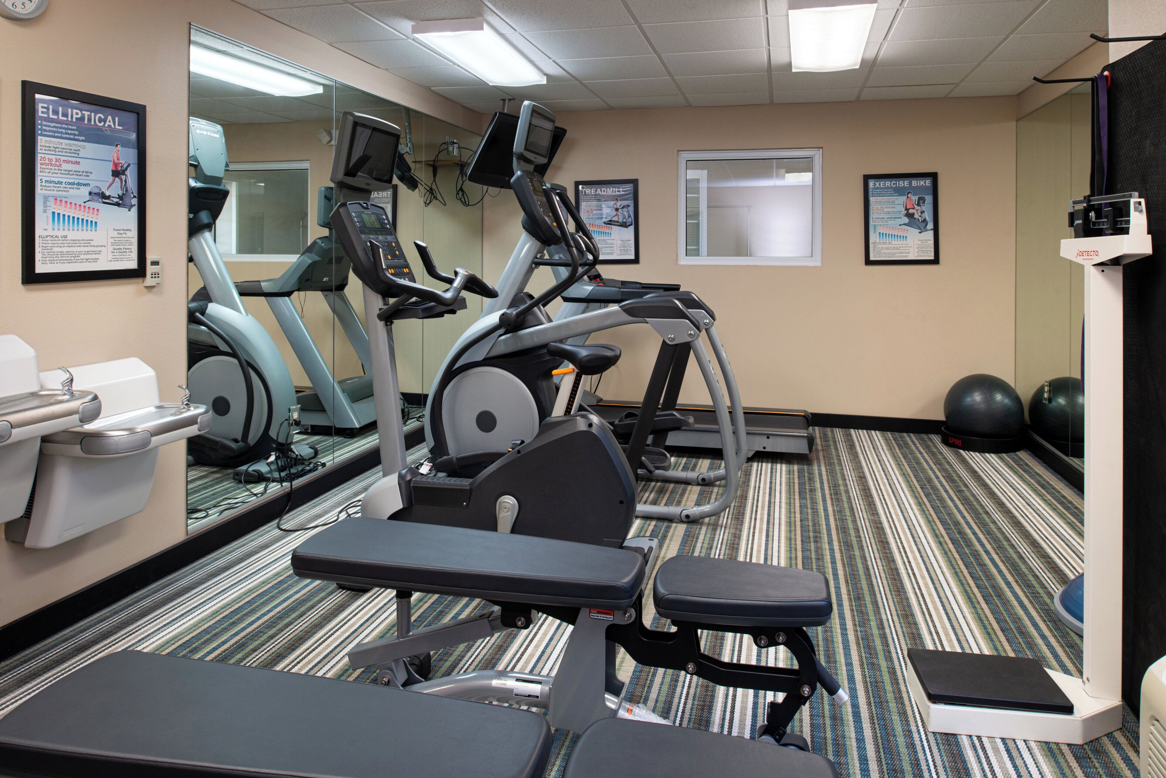 A fitness room with exercise bikes, treadmills, and a weight bench.