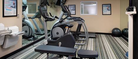 A fitness room with exercise bikes, treadmills, and a weight bench.