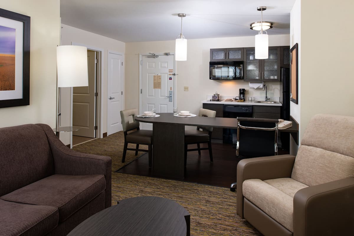 Habitación de hotel con comedor, kitchenette y zona de estar.