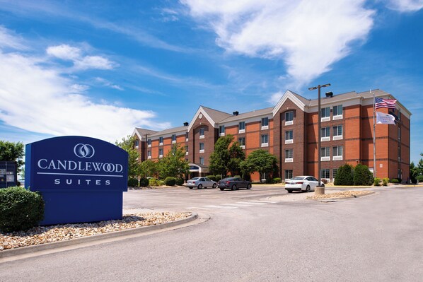Een hotelschiltje met 'Candlewood Suites' en een gebouw van baksteen met meerdere ramen en een vlag.