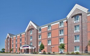 Un hôtel à plusieurs étages, doté d’une façade en briques, de grandes fenêtres et d’une entrée imposante avec une enseigne.