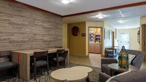 Un hall d’entrée moderne agrémenté d’un mur en bois, d’un espace café et de coins salon confortables.