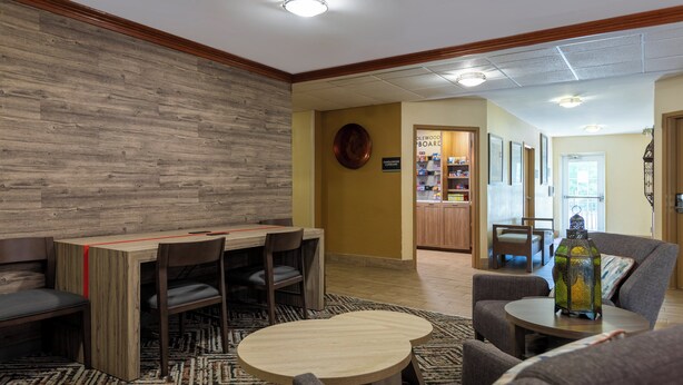 Un lobby moderno con una pared decorativa de madera, una estación de café y zonas de estar cómodas.