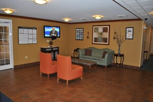 Un hall con televisión, un tablón de anuncios, un sofá y una mesa de centro.
