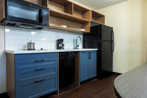 A modern kitchen with a microwave, coffee maker, dishwasher, and refrigerator. - Candlewood Suites Colonial Heights Fort Lee by IHG (Colonial Heights)