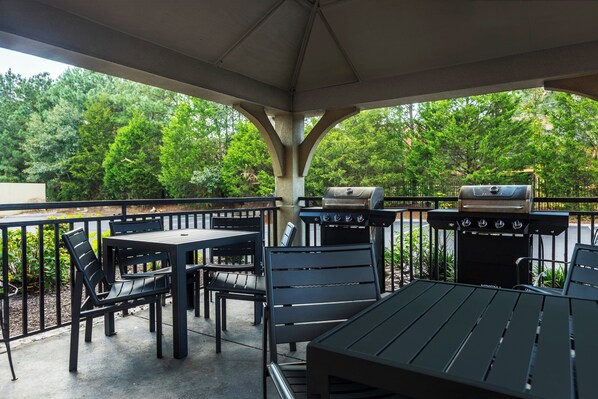 An outdoor patio with a covered seating area, a grill, and a view of the surrounding greenery. - Candlewood Suites Colonial Heights Fort Lee by IHG (Colonial Heights)