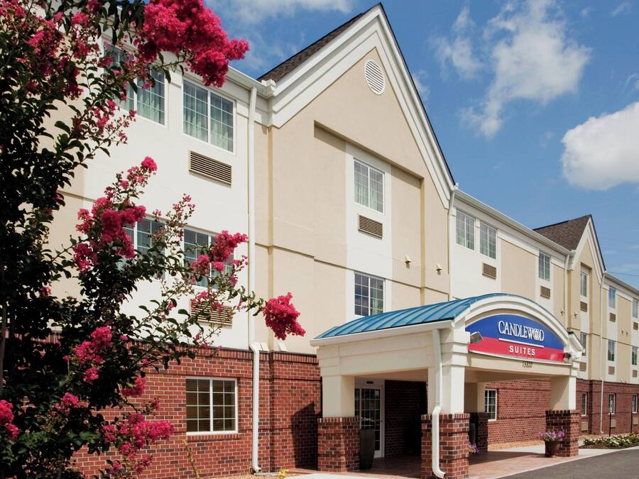 A hotel with a white facade, a blue awning, and a sign that reads 'CANDLEWOOD SUITES'.