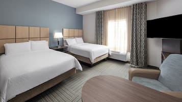 A hotel room with two beds, a TV, a desk, and a chair.