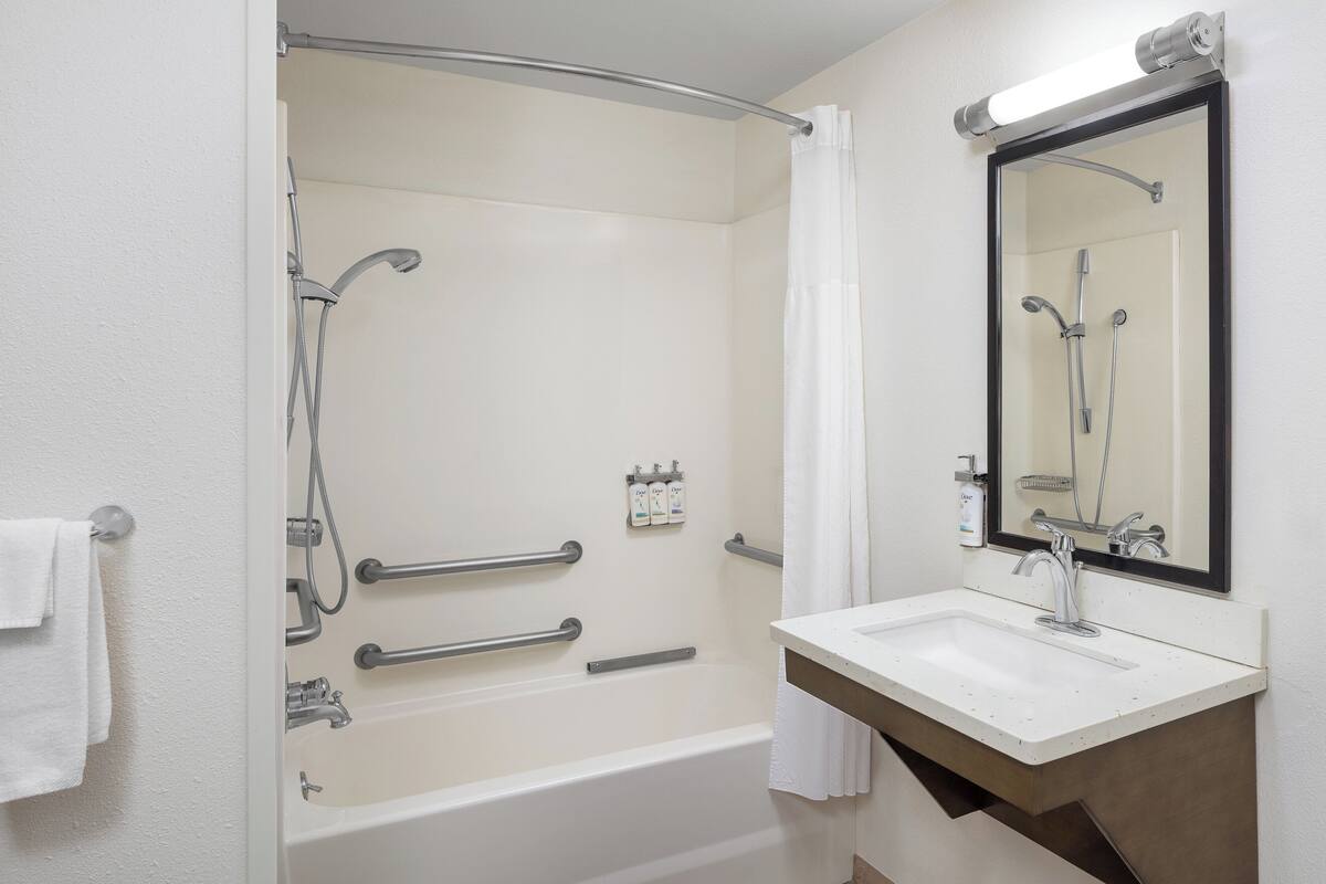Un baño moderno con bañera, ducha, lavamanos y espejo.