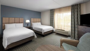 Una habitación de hotel con dos camas, televisión, escritorio y silla.