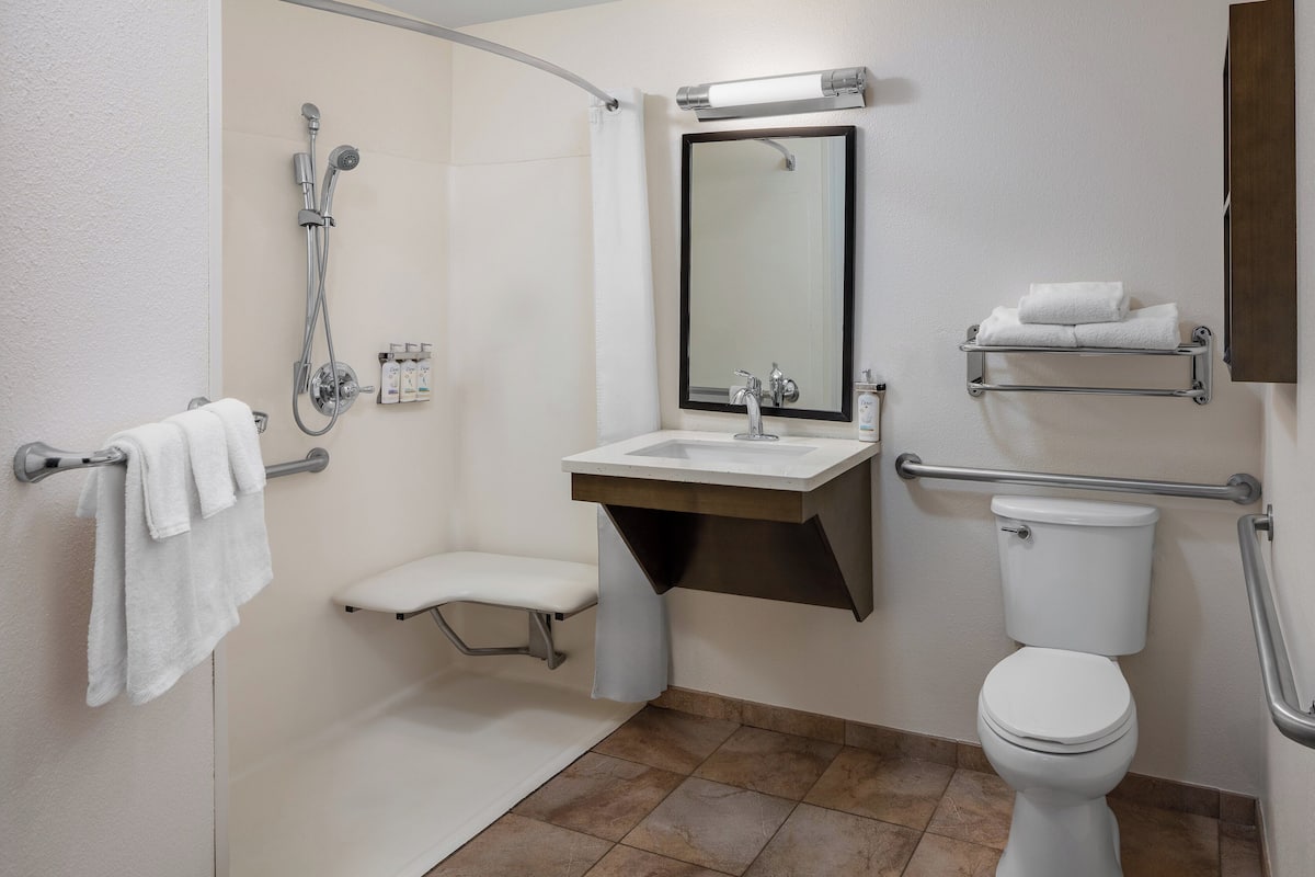 Un baño moderno con ducha, inodoro, lavabo y espejo.