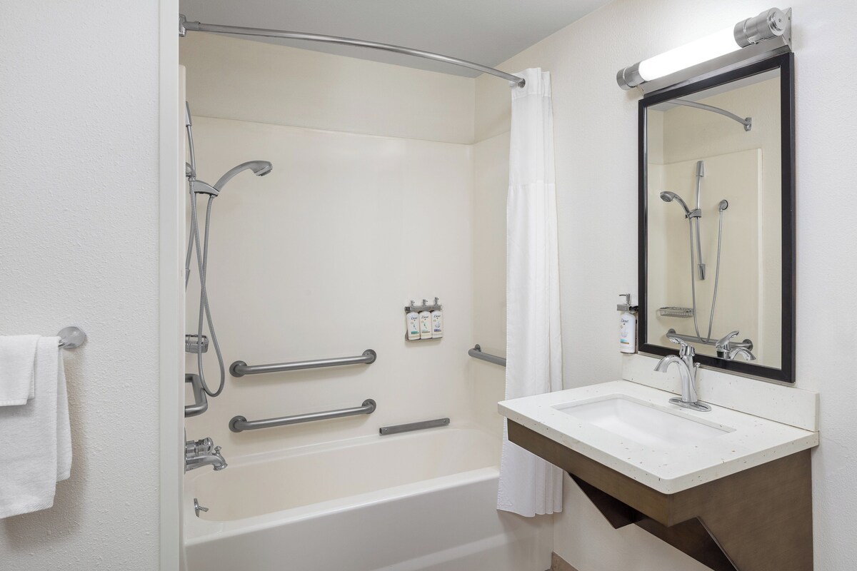 A modern bathroom with a bathtub, a shower, a sink, and a mirror.
