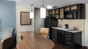 Una cocina moderna con zona de comedor, que incluye una mesa y sillas de madera, un microondas integrado y una cafetera.
