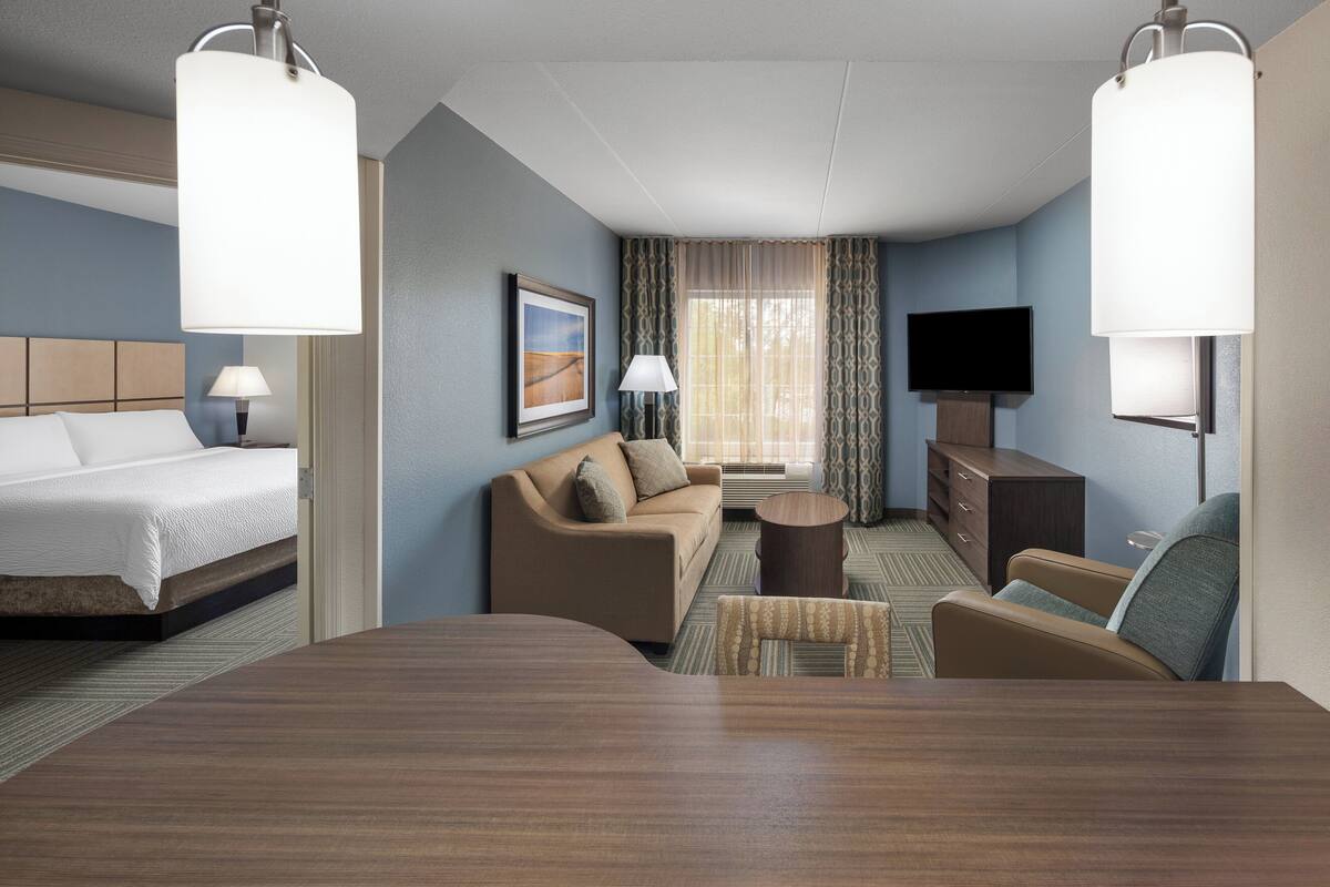 Una habitación de hotel con cama, sofá, mesa de centro y televisión.