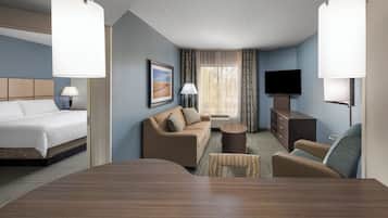 A hotel room with a bed, a sofa, a coffee table, and a TV.